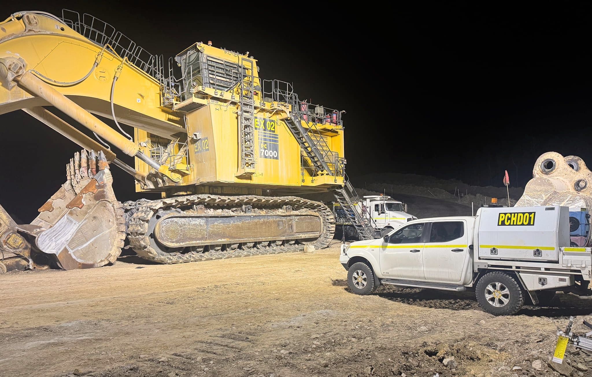 A Komatsu PC7000 mining excavator at night with a Port City service ute parked beside it
