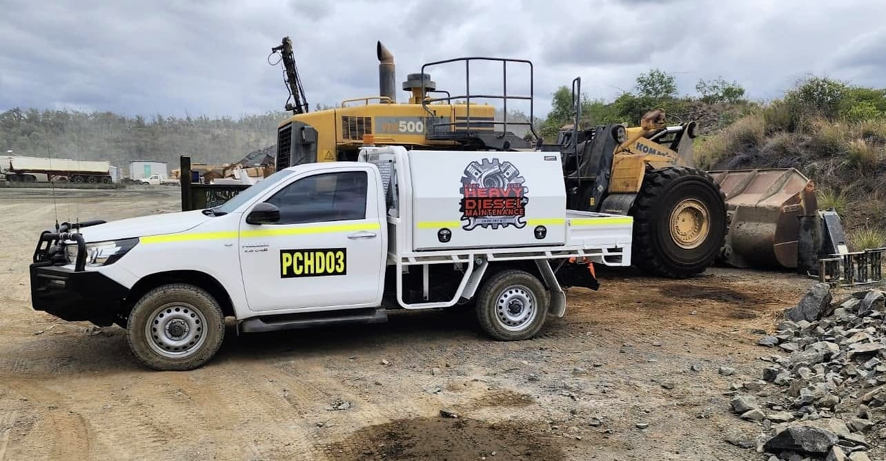 A Port City service ute on a quarry site beside a wheel loader